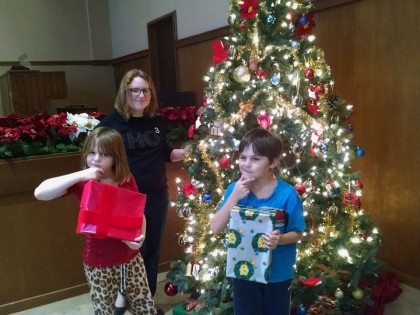Children looking at presents by a lighted Christmas tree