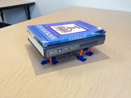 Two books suspended on a system of straws, paperclips, and tape